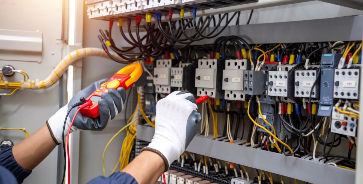 Techniker prüft elektrische Verbindungen im Schaltschrank – Trennung von Strom- und LWL Verlegekabeln notwendig