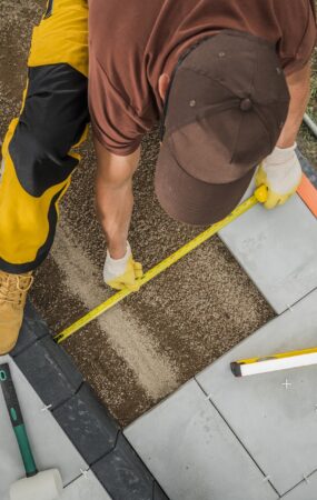 Handwerker verlegt Terrassenplatten | Terrassenüberdachung Düsseldorf