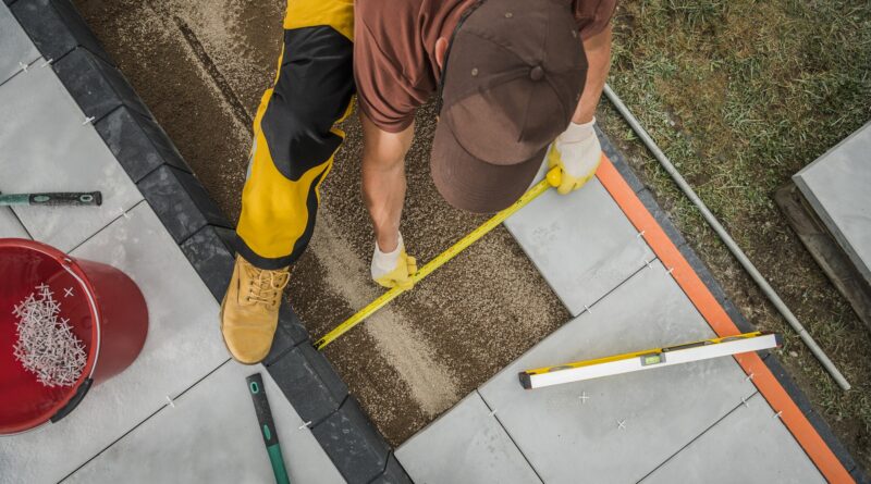 Handwerker verlegt Terrassenplatten | Terrassenüberdachung Düsseldorf